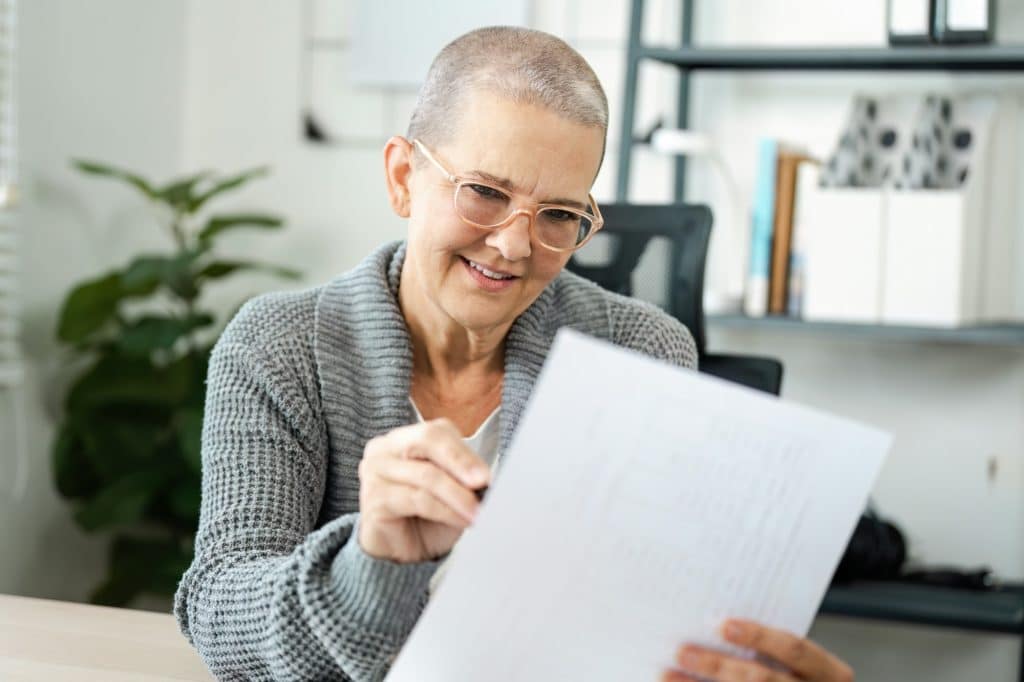 Senior Woman Reviewing Documents in a Modern Office Setting with a Smile